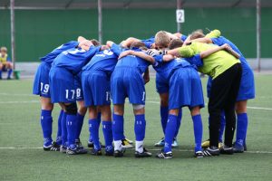 Equipo deportivo infantil abrazados en corro.